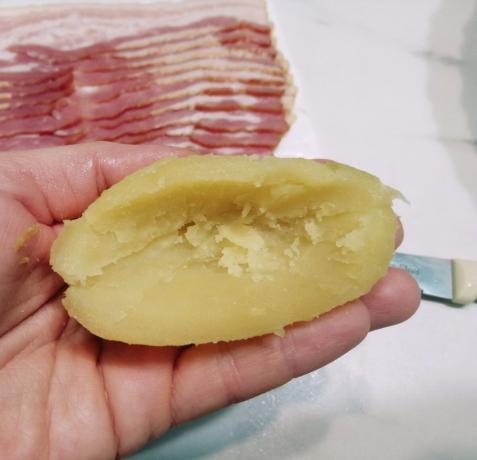 Patatesleri soyun, dikkatlice orta kesip bıçakla ortadan ikiye kesilmiş